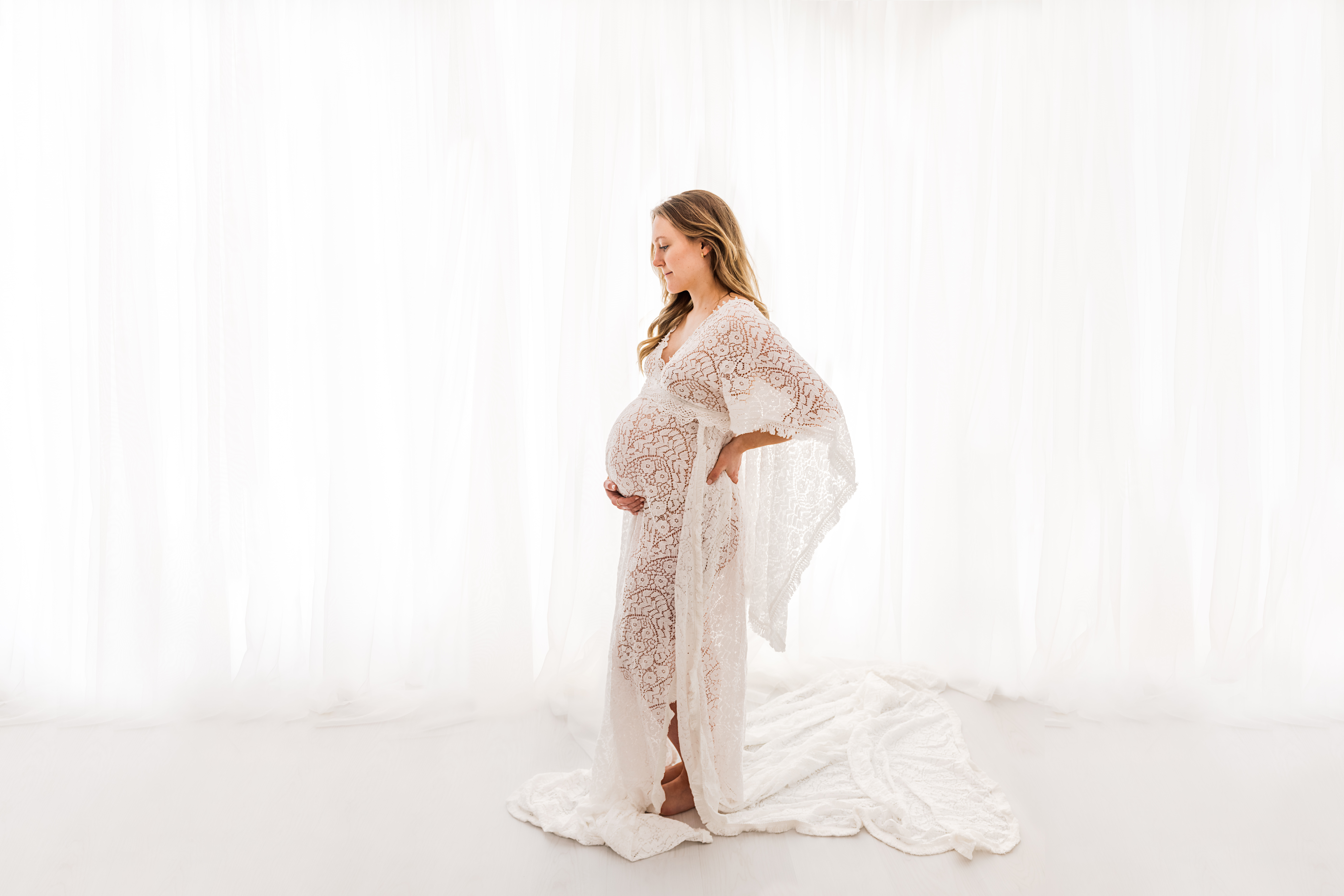 Pregnant woman in lacey dress looking at belly
