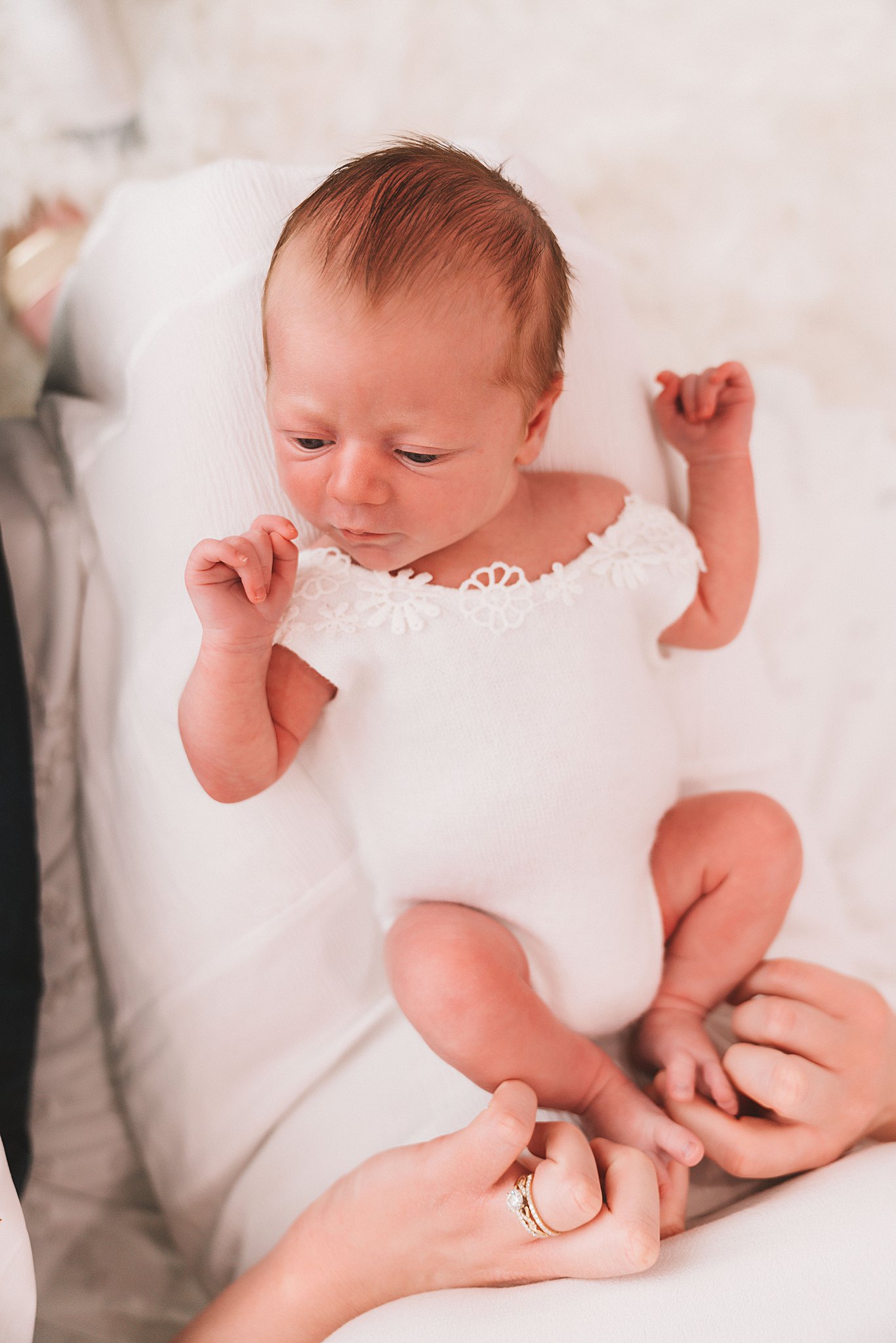 A newborn baby lays in her mother's lap while mom plays with her toes midwest fetal care center