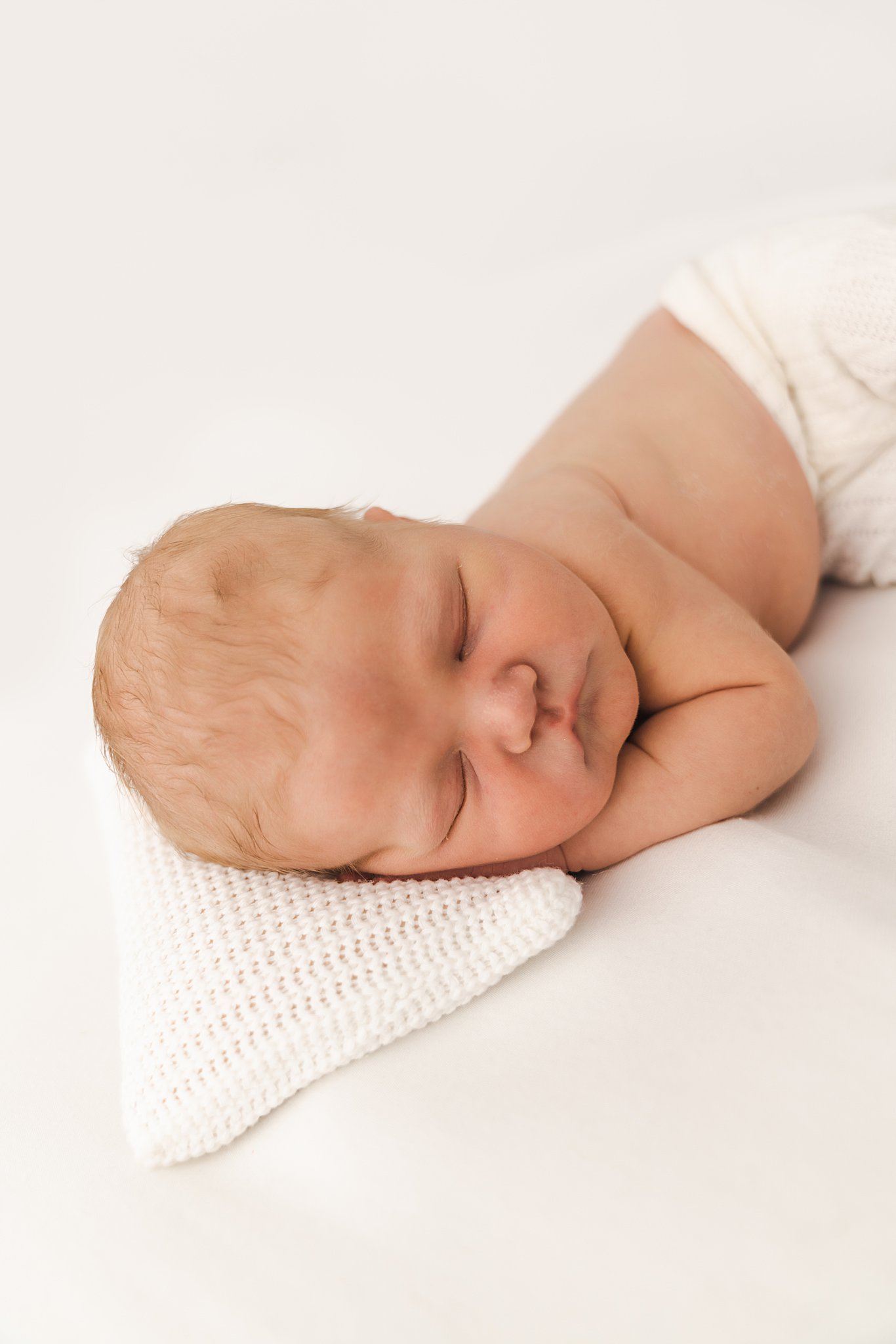 A newborn baby sleeps on a small pillow in a studio north star newborns